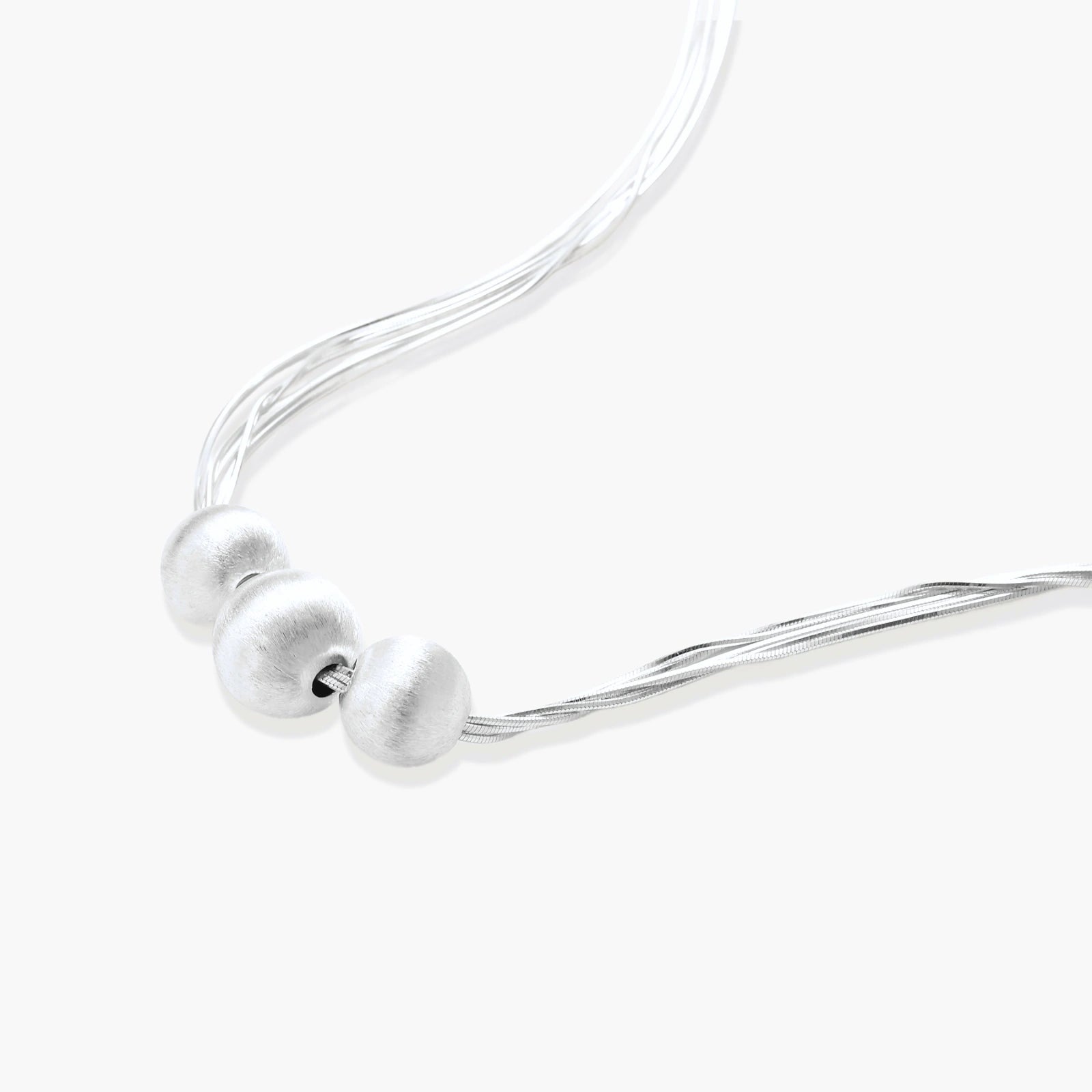 Sterling silver multi-strand necklace with three brushed round beads on cream background
