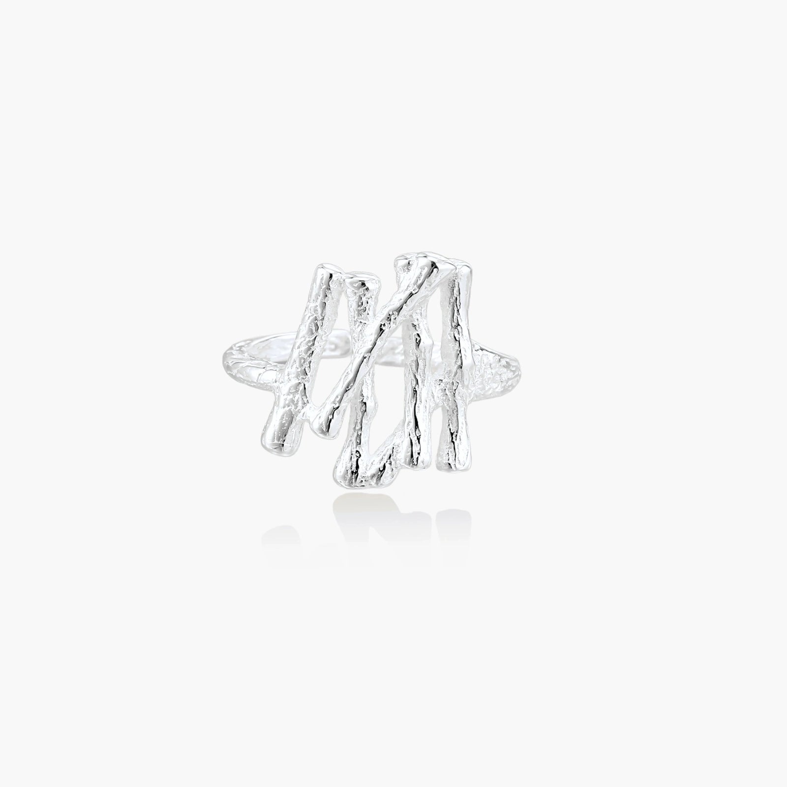 Sculptural sterling silver ring with organic branch design and textured surfaces on cream background