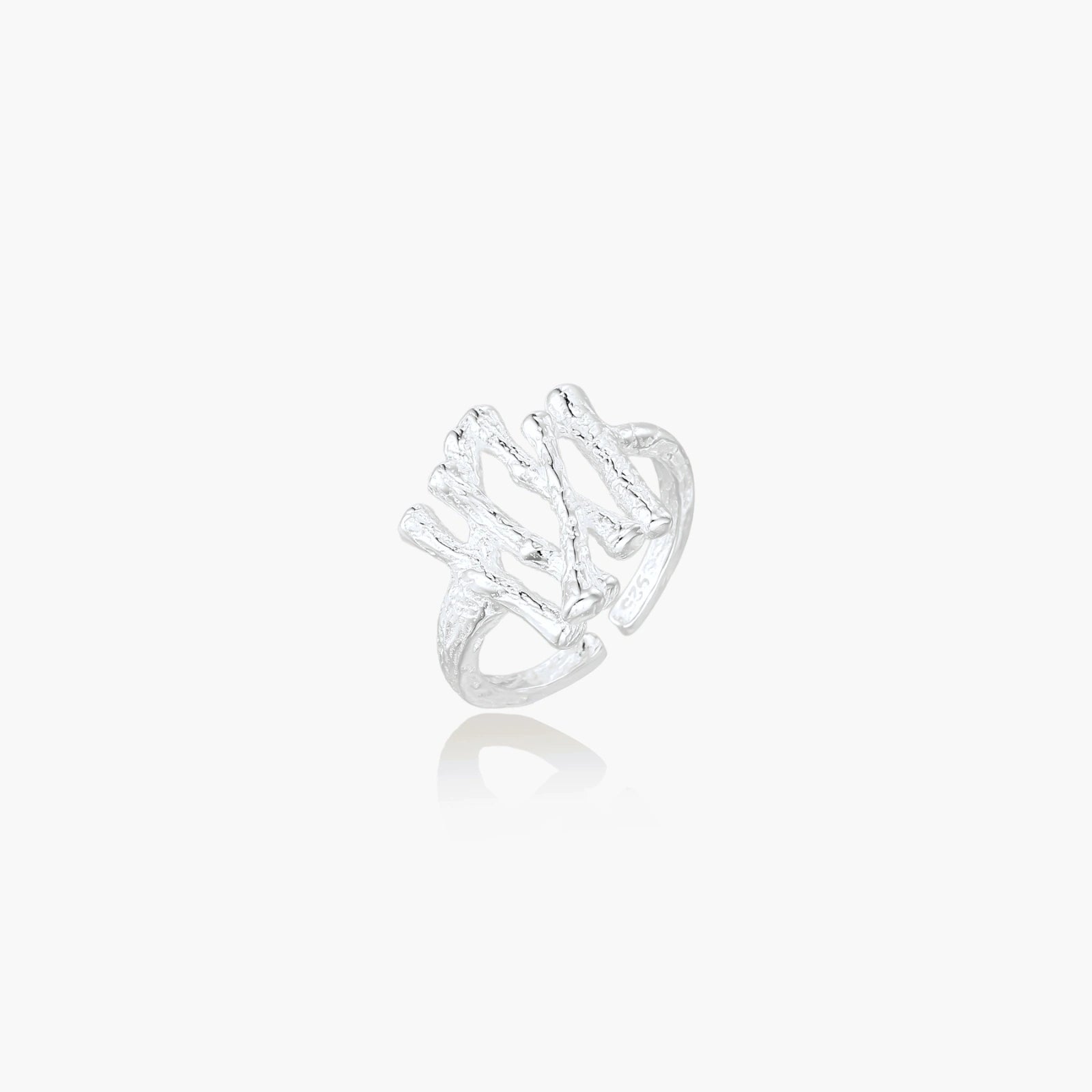 Sculptural sterling silver ring with organic branch design and textured surfaces on cream background