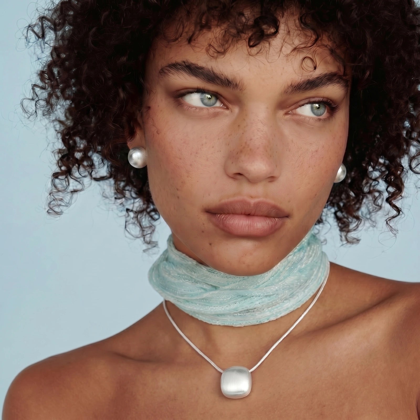 Woman wearing a light blue scarf and pearl necklace against a light blue background