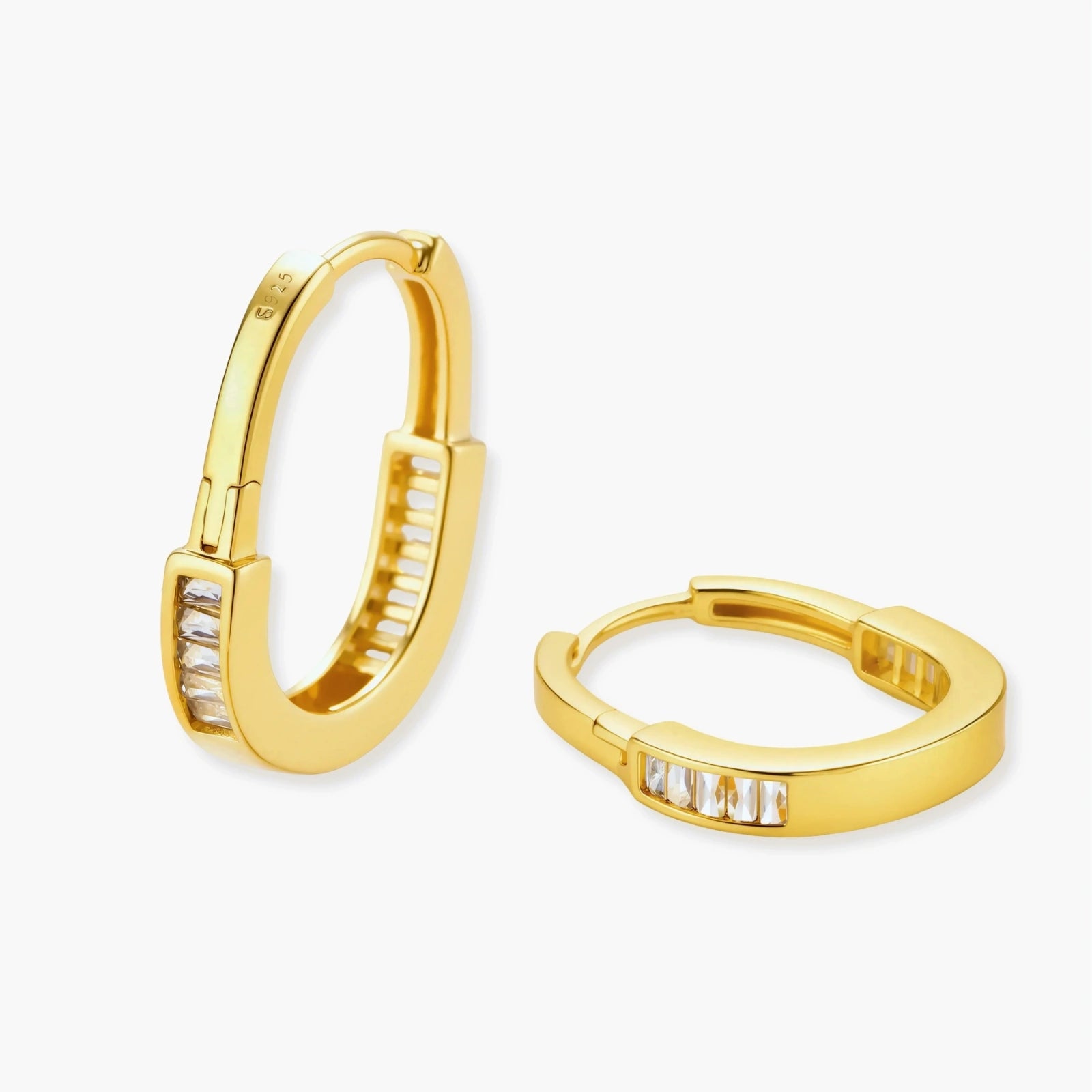 Close-up of gold-plated sterling silver huggie hoop earrings featuring rectangular cubic zirconia stones on neutral background.