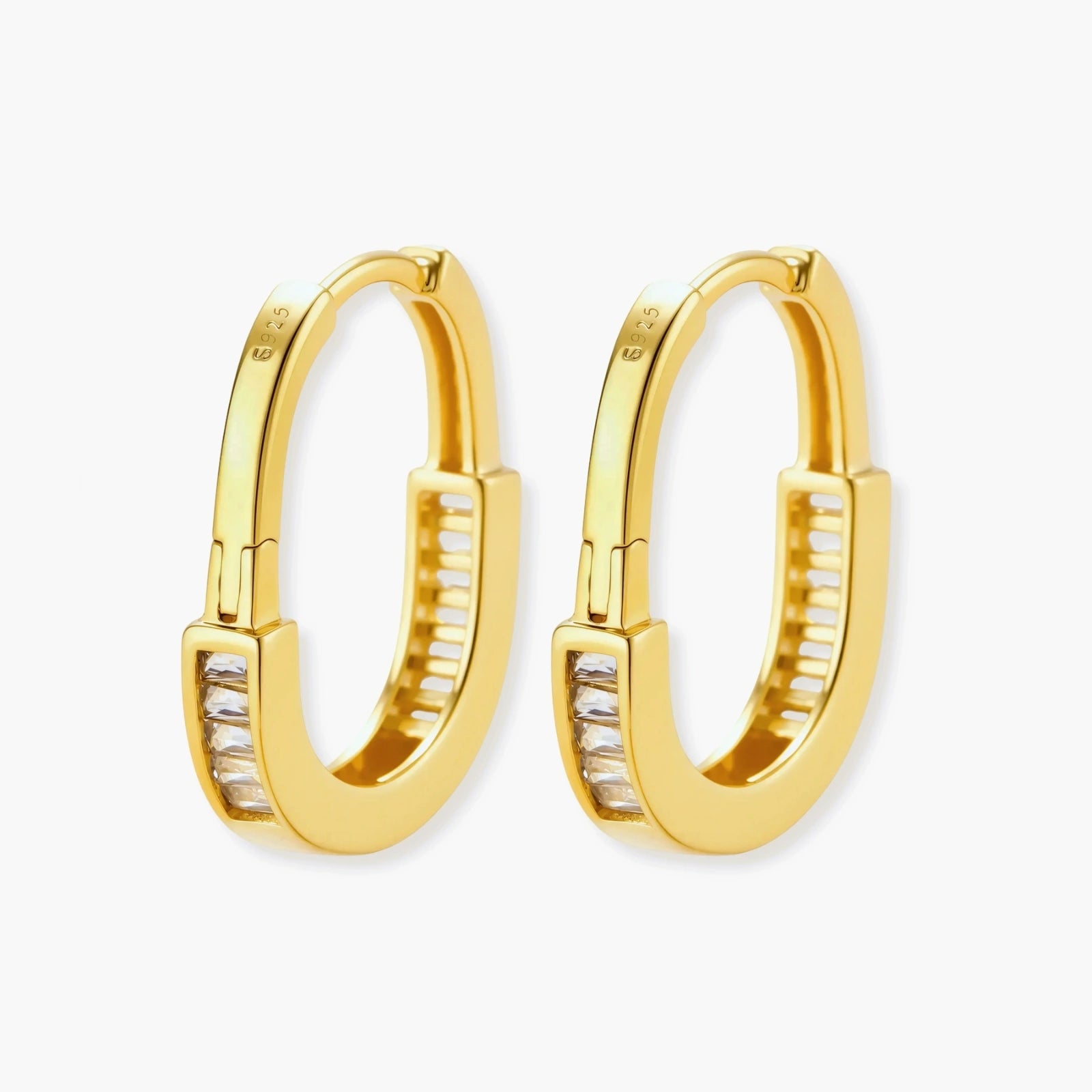 Close-up of gold-plated sterling silver huggie hoop earrings featuring rectangular cubic zirconia stones on neutral background.