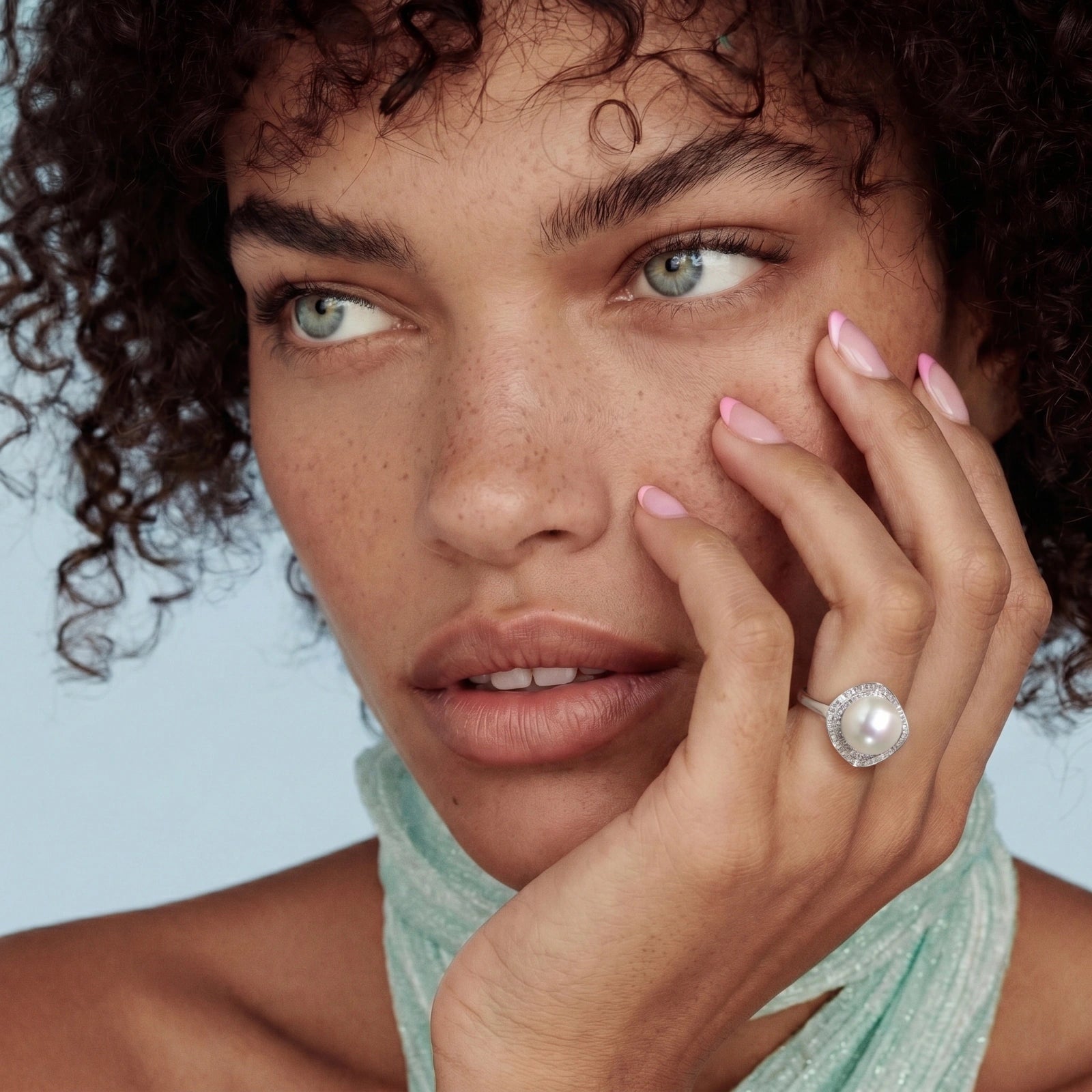 Woman wearing a pearl ring with a light blue background