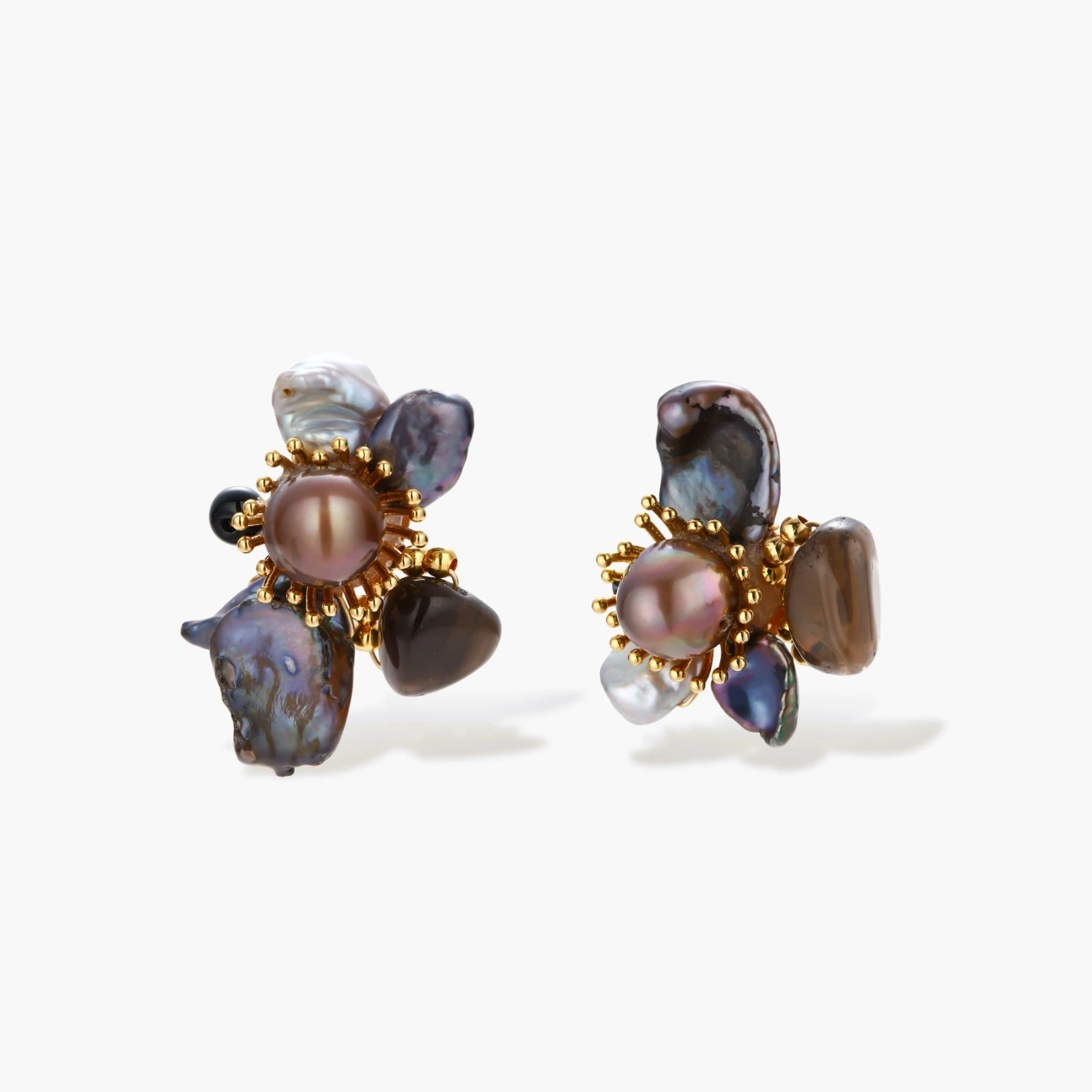 Dark baroque pearl cluster earrings with gold sunburst centers arranged in organic floral design on cream background.