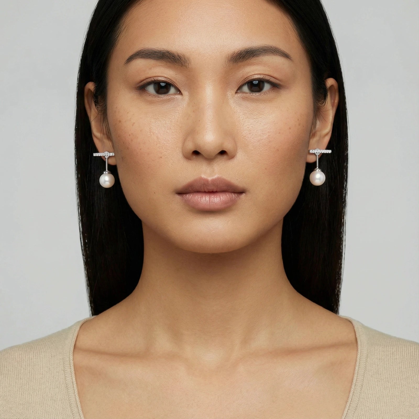Woman wearing pearl earrings against a plain background