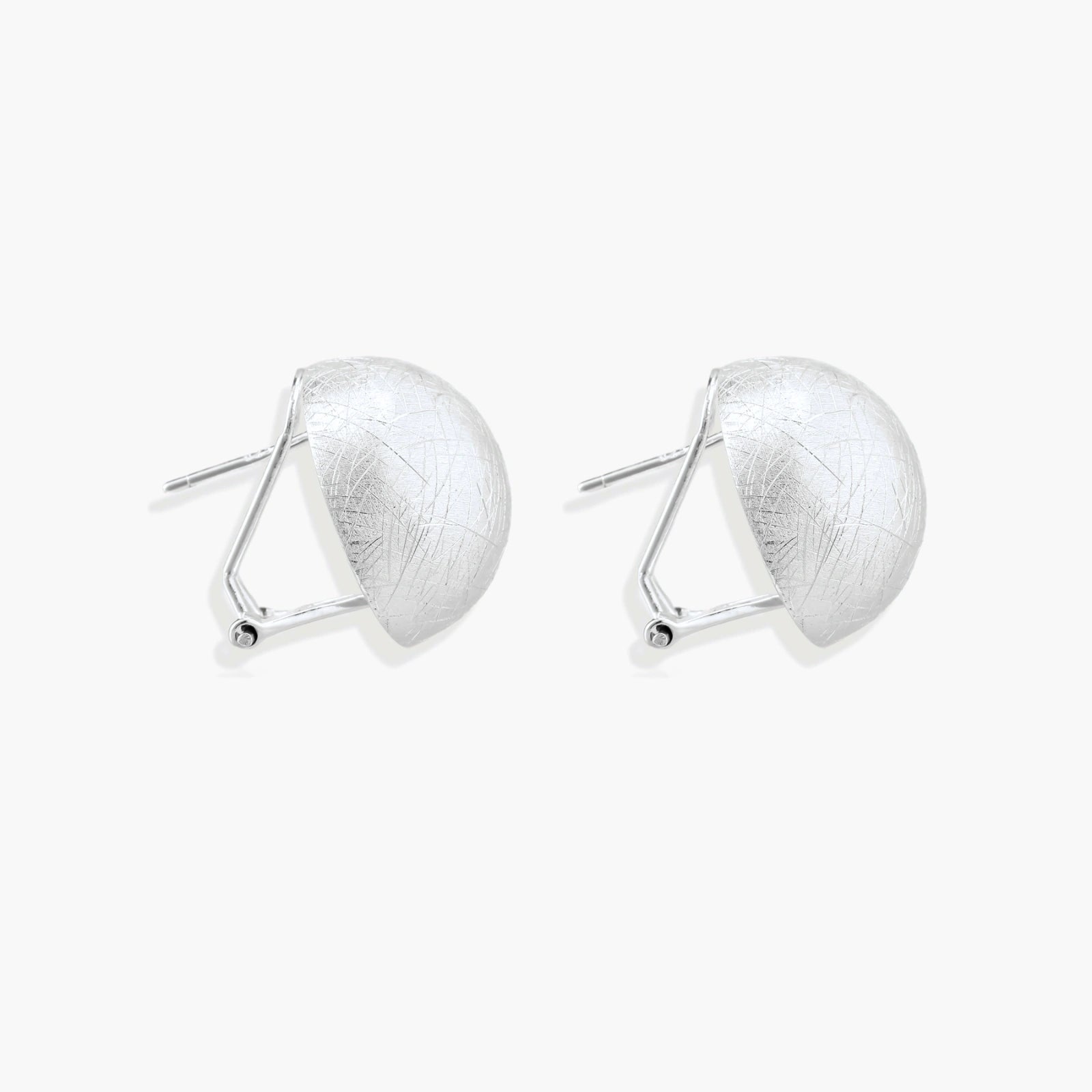 Brushed sterling silver half-dome clip-on earrings with textured surface against cream background