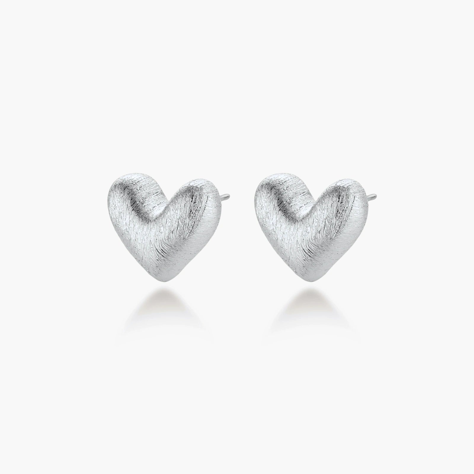 Pair of brushed platinum-plated 925 sterling silver puffy heart stud earrings on a cream background.