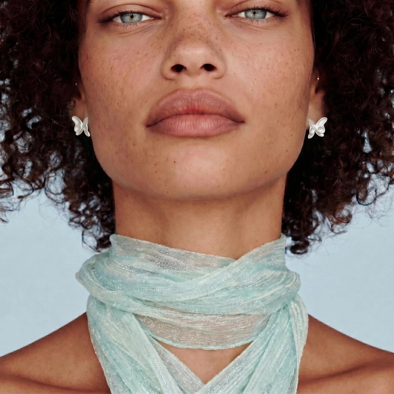 Woman wearing a light blue scarf with a plain background