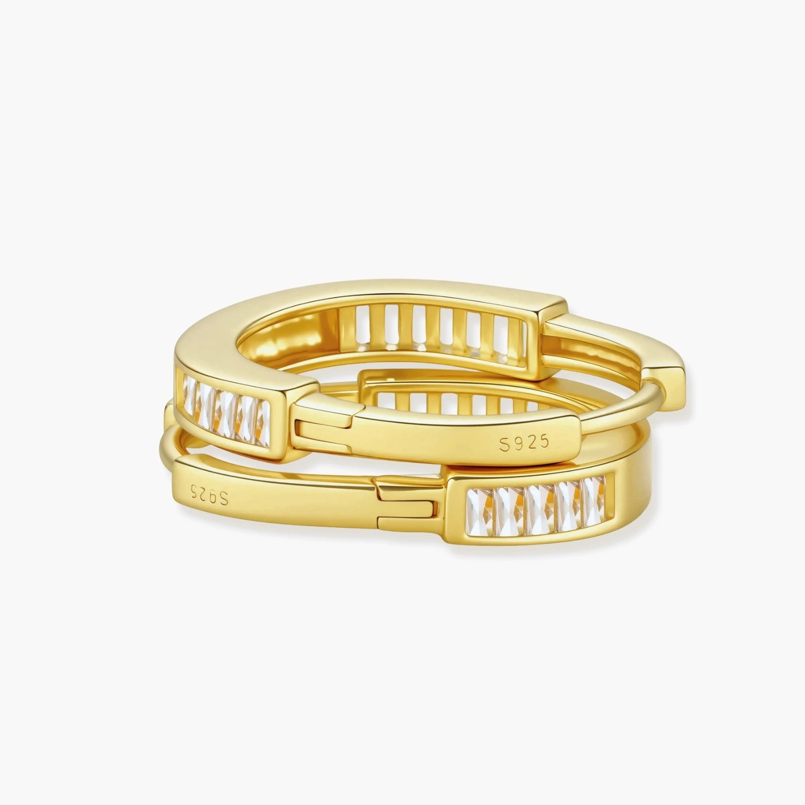 Close-up of gold-plated sterling silver huggie hoop earrings featuring rectangular cubic zirconia stones on neutral background.