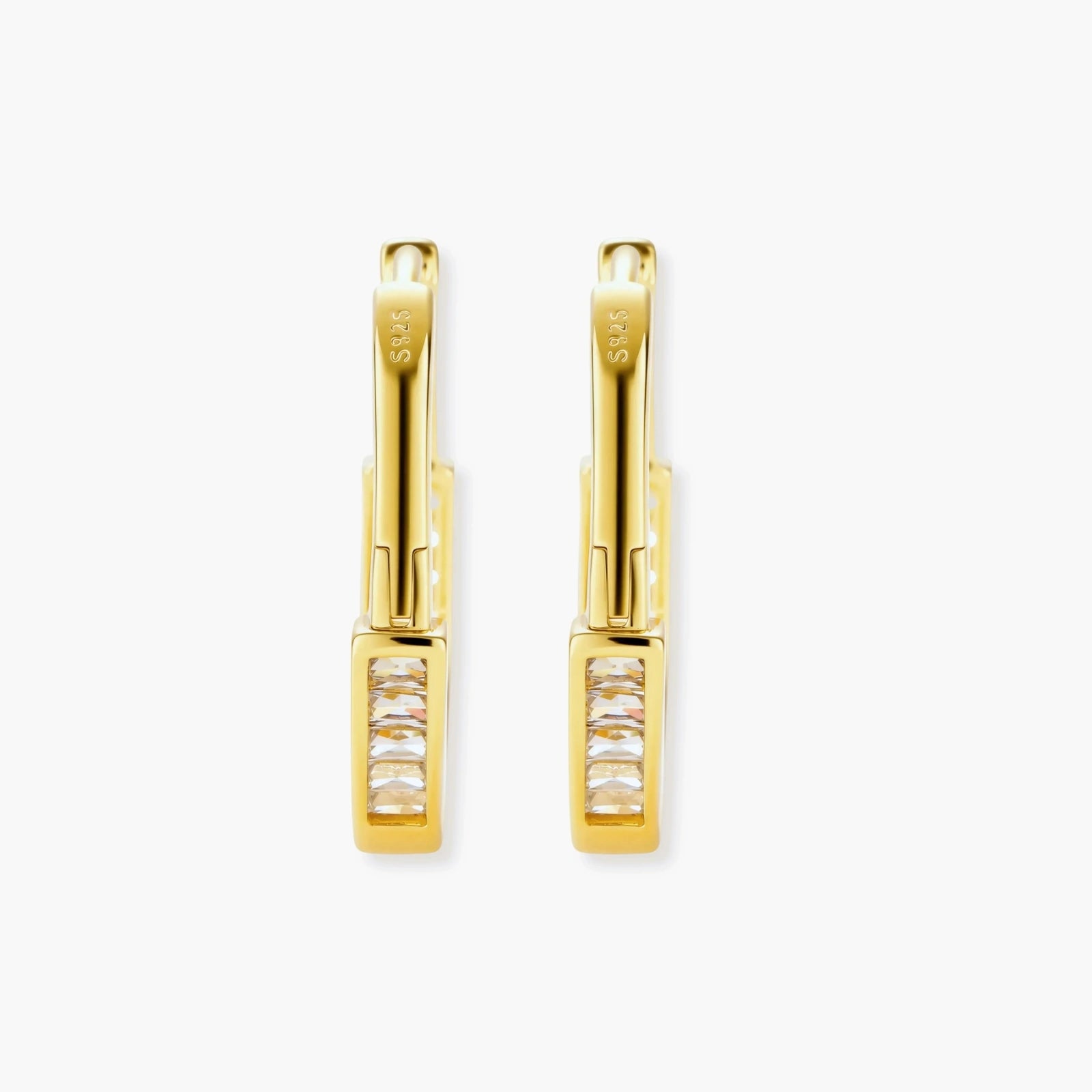 Close-up of gold-plated sterling silver huggie hoop earrings featuring rectangular cubic zirconia stones on neutral background.
