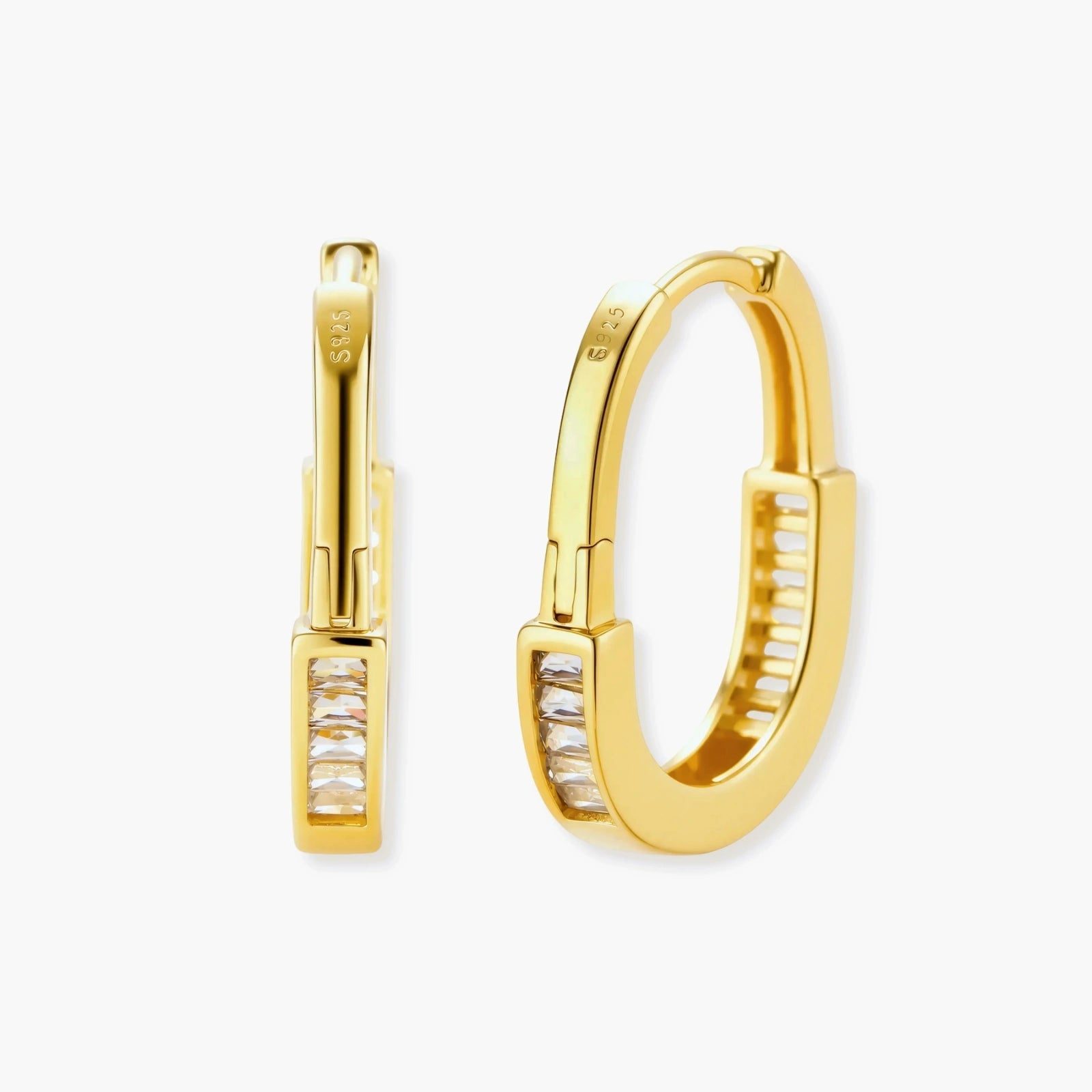 Close-up of gold-plated sterling silver huggie hoop earrings featuring rectangular cubic zirconia stones on neutral background.