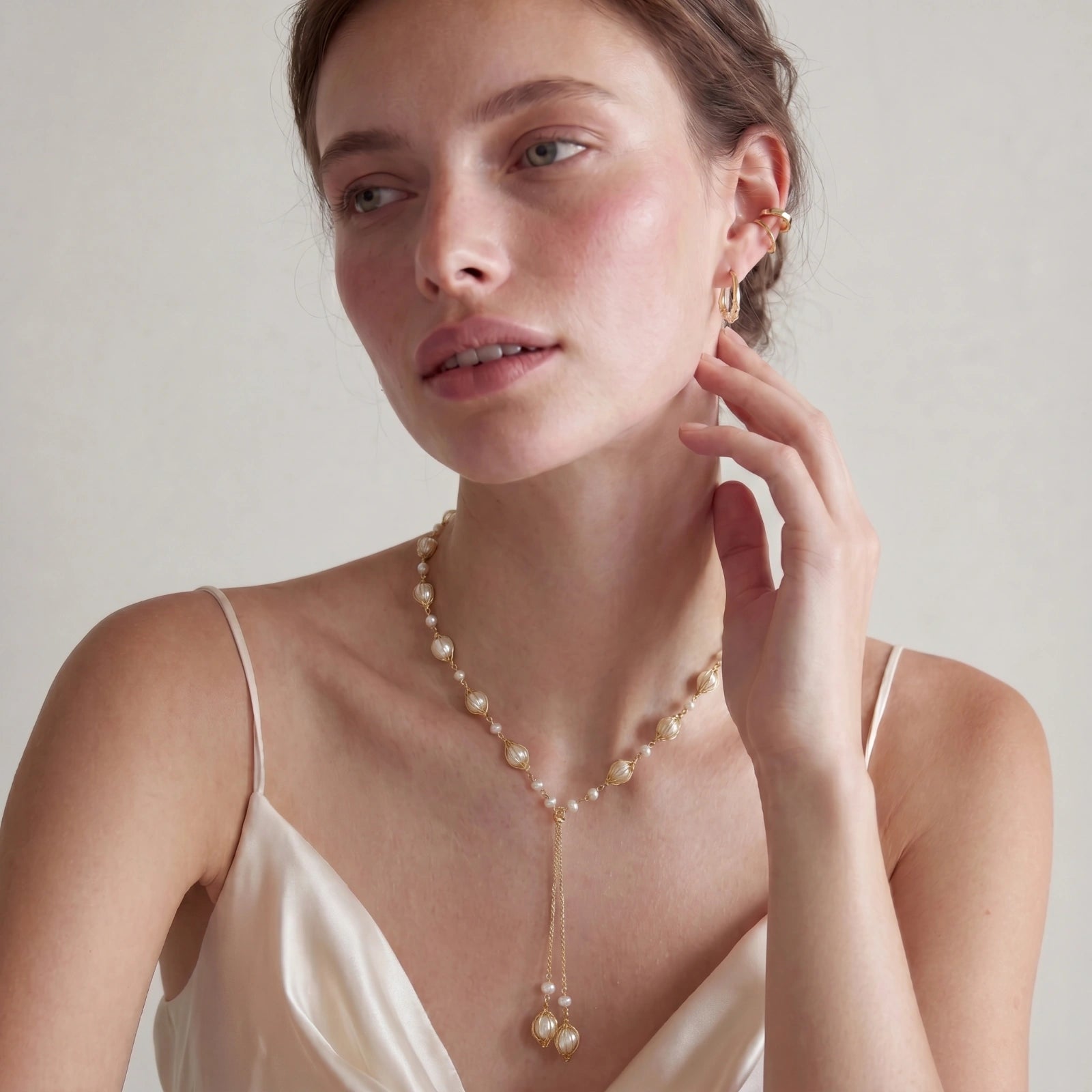 Woman wearing a pearl necklace and earrings on a plain background
