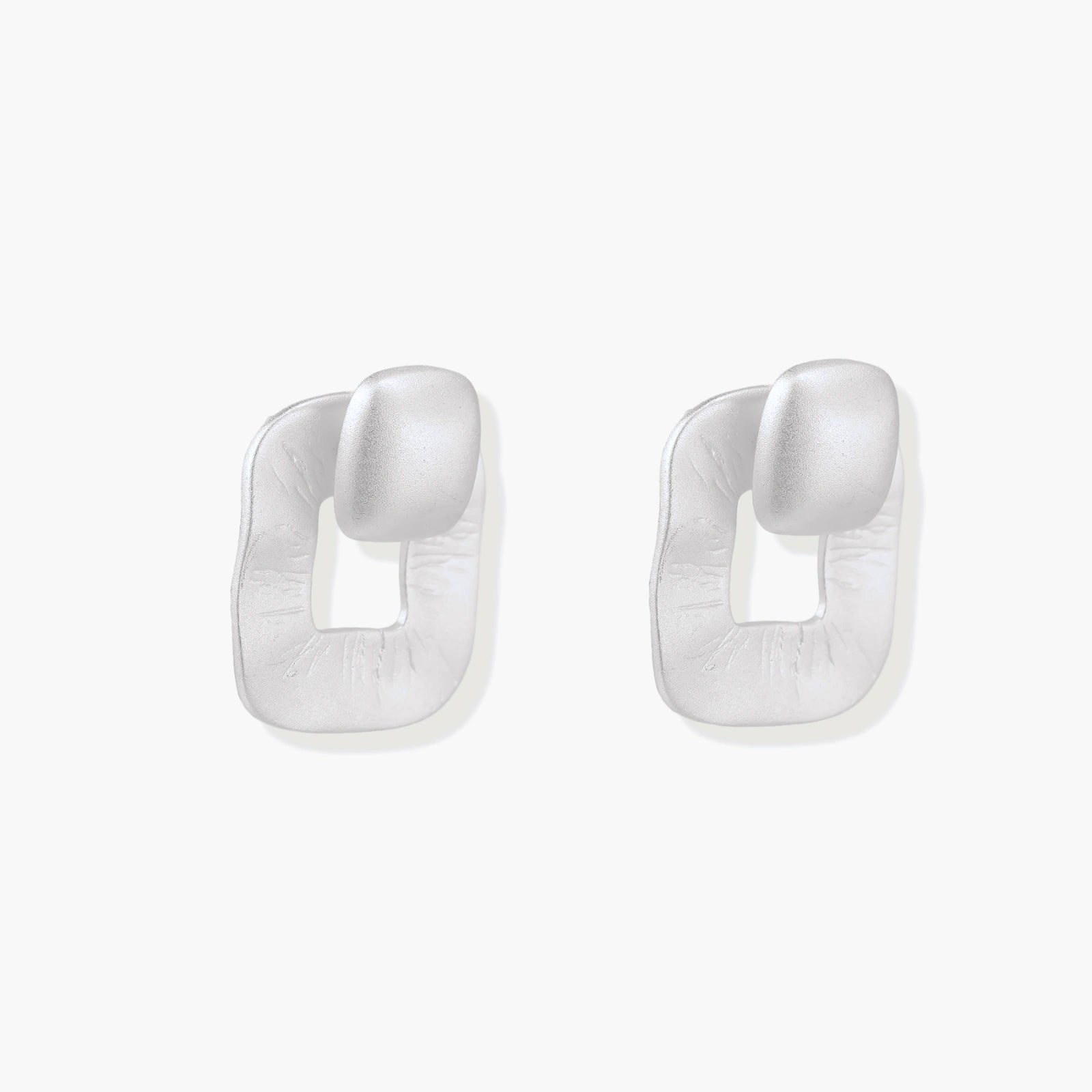 Pair of geometric sterling silver earrings with frosted square frames and glossy rounded studs on white background